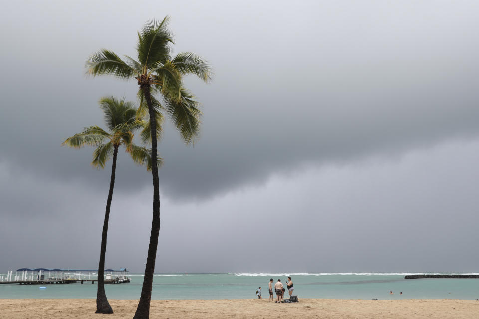 With storm clouds in the background, beachgoers are seen on Waikiki Beach, Monday, Dec. 6, 2021, in Honolulu. (AP Photo/Marco Garcia)