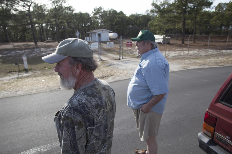 Flemington Road community resident Sam Malpass, left, and Kenneth Sandlin of Wilmington, North Carolina, stand outside the well water treatment plant that services their homes on Wednesday, Feb. 19, 2014. The neighbors are part of the small community nearby the L.V. Sutton Complex operated by Duke Energy they feel could be polluting well water with spill off and seepage from large coal ash ponds. (AP Photo/Randall Hill)