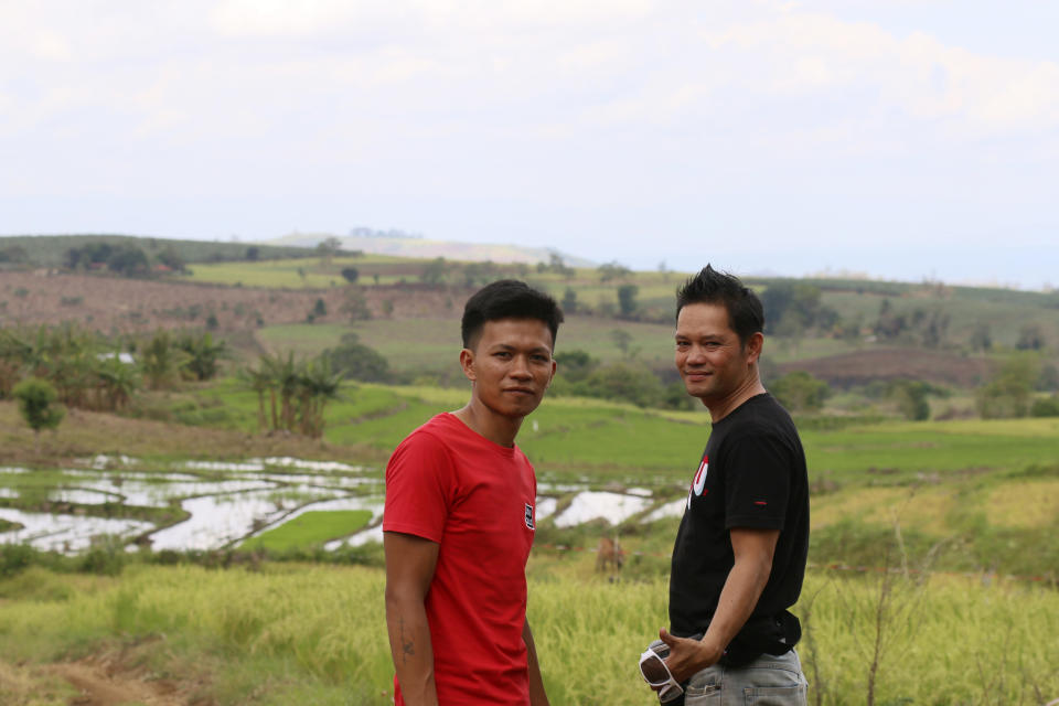 Joemar Flores, and his neighbor, Junthan Giumba pose for a photo with Flores' rice paddies visible in the distance in Mindanao, Philippines, May 9, 2024. A growing type of insurance, called parametric insurance, is helping farmers like Flores and others in developing countries respond to extreme weather events. (Bill Spindle/Cipher News via AP)