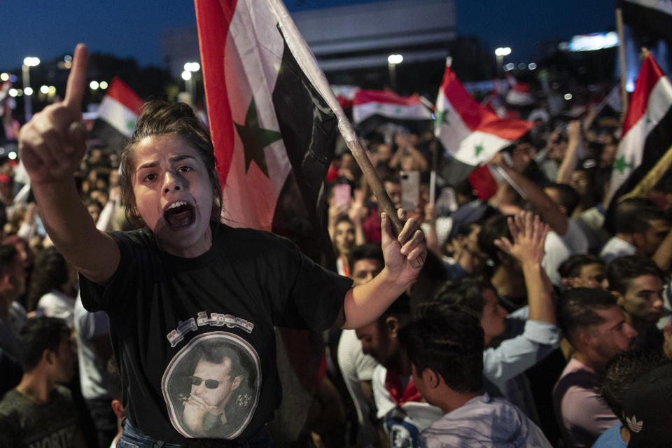 Syrian President Bashar Assad supporters hold up national flags and pictures of Assad as they celebrate at Omayyad Square, in Damascus, Syria, Thursday, May 27, 2021. (AP Photo/Hassan Ammar)