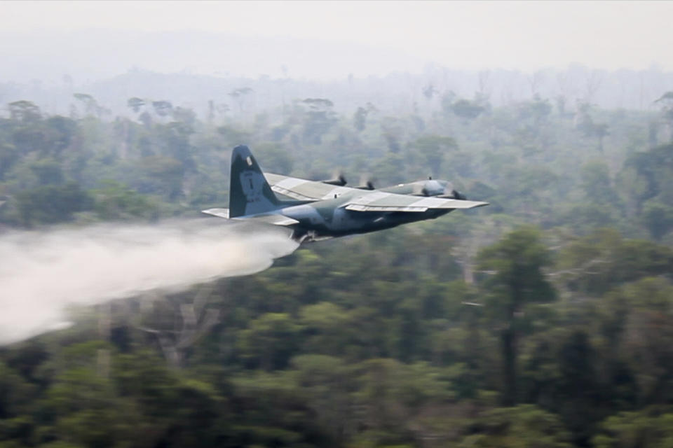 In this photo released by Brazil Ministry of Defense, a C-130 Hercules aircraft dumps water to fight fires burning in the Amazon rainforest, in Brazil, Saturday, Aug, 24, 2019. Backed by military aircraft, Brazilian troops on Saturday were deploying in the Amazon to fight fires that have swept the region and prompted anti-government protests as well as an international outcry. (Brazil Ministry of Defense via AP)