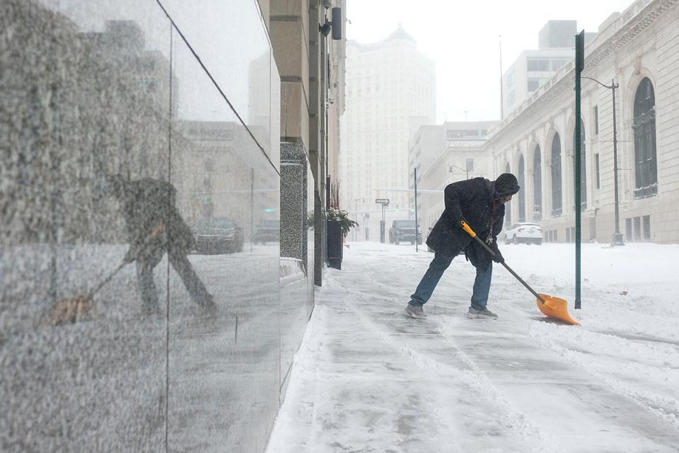 24 December 2022: A man tries to remove snow from the sidewalk in downtown Detroit, United States (Getty)