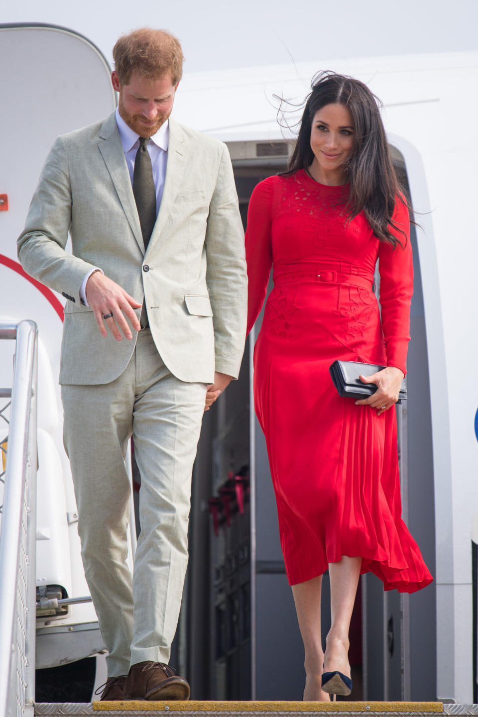 File photo dated 25/10/18 of the Duke and Duchess of Sussex arriving at Fua'amotu Airport, Tonga, with Meghan wearing a &pound;345 red outfit by London fashion brand Self-Portrait.