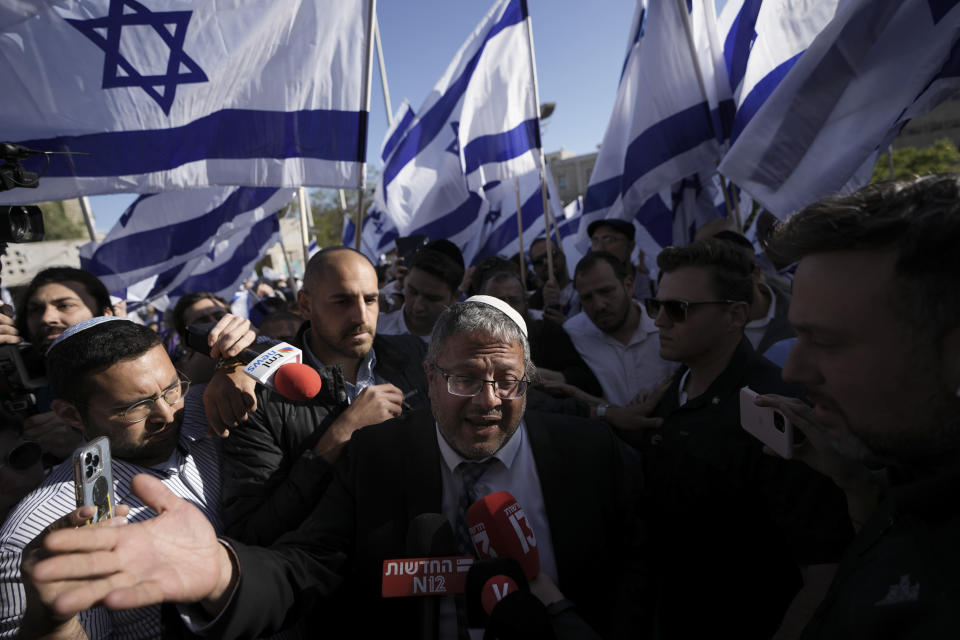 Israeli lawmaker Itamar Ben-Gvir, center, surrounded by right wing activists with Israeli flags, speaks to the media as they gather for a march in Jerusalem, Wednesday, April 20, 2022. The group of Israeli ultra-nationalists said it is determined to go ahead with a flag-waving march around predominantly Palestinian areas of Jerusalem's Old City, brushing aside a police ban of an event that served as one of the triggers of last year's Israel-Gaza war. (AP Photo/Ariel Schalit)