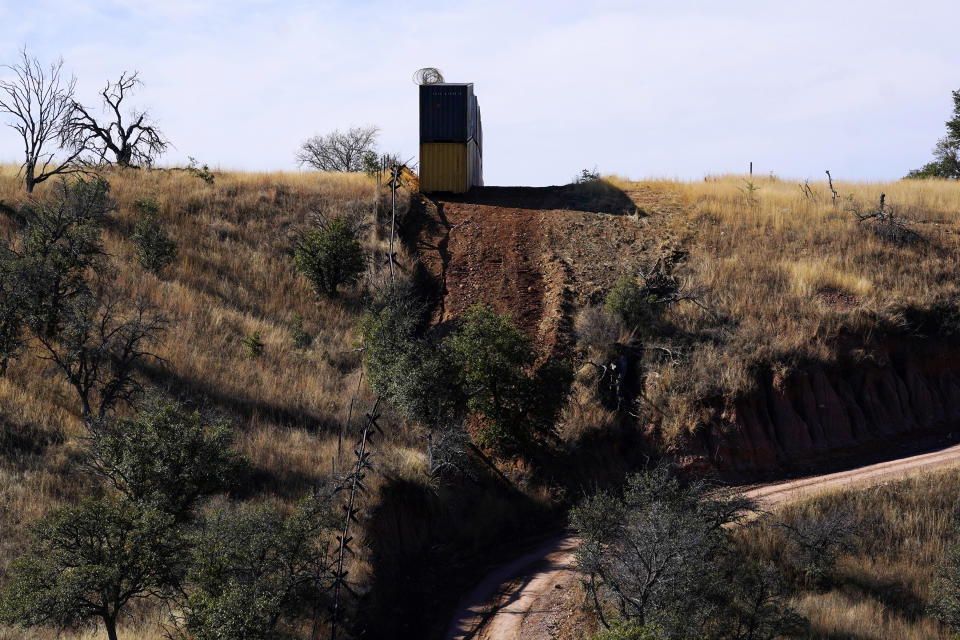 A row of double staked shipping containers abruptly ends at the start of a steep wash along the border between the United States and Mexico in San Rafael Valley, Ariz., Thursday, Dec. 8, 2022. Work crews are steadily erecting hundreds of double-stacked shipping containers along the rugged east end of Arizona’s boundary with Mexico as Republican Gov. Doug Ducey makes a bold show of border enforcement even as he prepares to step aside next month for Democratic Governor-elect Katie Hobbs. (AP Photo/Ross D. Franklin)