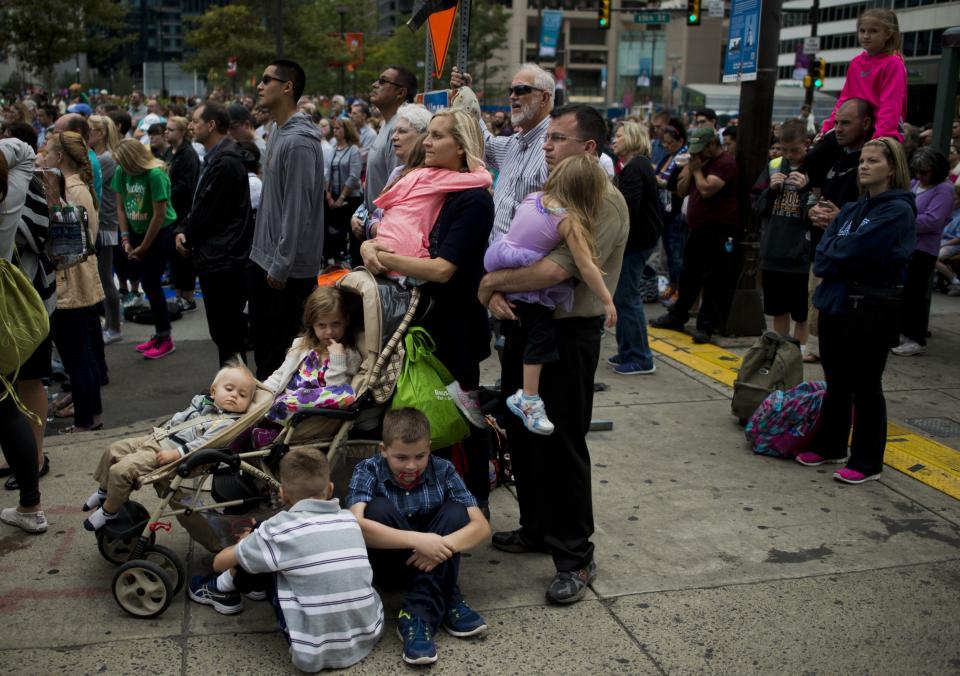 A family watches a Mass on a large screen with Pope Francis in downtown Philadelphia.