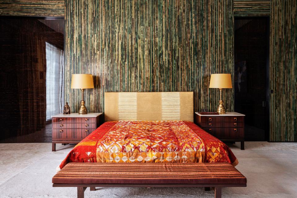 Painted stripes decorate the master bedroom, where antique Phulkari textiles cover the custom bed. Antique Josef Hoffmann table lamps.