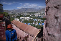 A staff member stands on a rampart at the Potala Palace overlooking the modern city skyline of Lhasa in western China's Tibet Autonomous Region, as seen during a rare government-led tour of the region for foreign journalists, Tuesday, June 1, 2021. Long defined by its Buddhist culture, Tibet is facing a push for assimilation and political orthodoxy under China's ruling Communist Party. (AP Photo/Mark Schiefelbein)