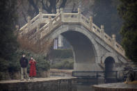 A couple wear face masks as they walk at a public park in Beijing, Saturday, Feb. 29, 2020. The coronavirus outbreak's impact on the world economy grew more alarming on Saturday, even as President Donald Trump denounced criticisms of his response to the threat as a "hoax" cooked up by his political enemies. (AP Photo/Mark Schiefelbein)