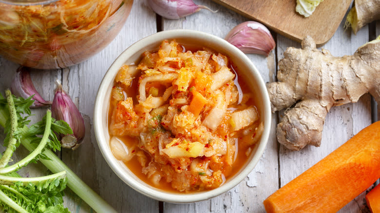 Kimchi in white bowl with aromatics around