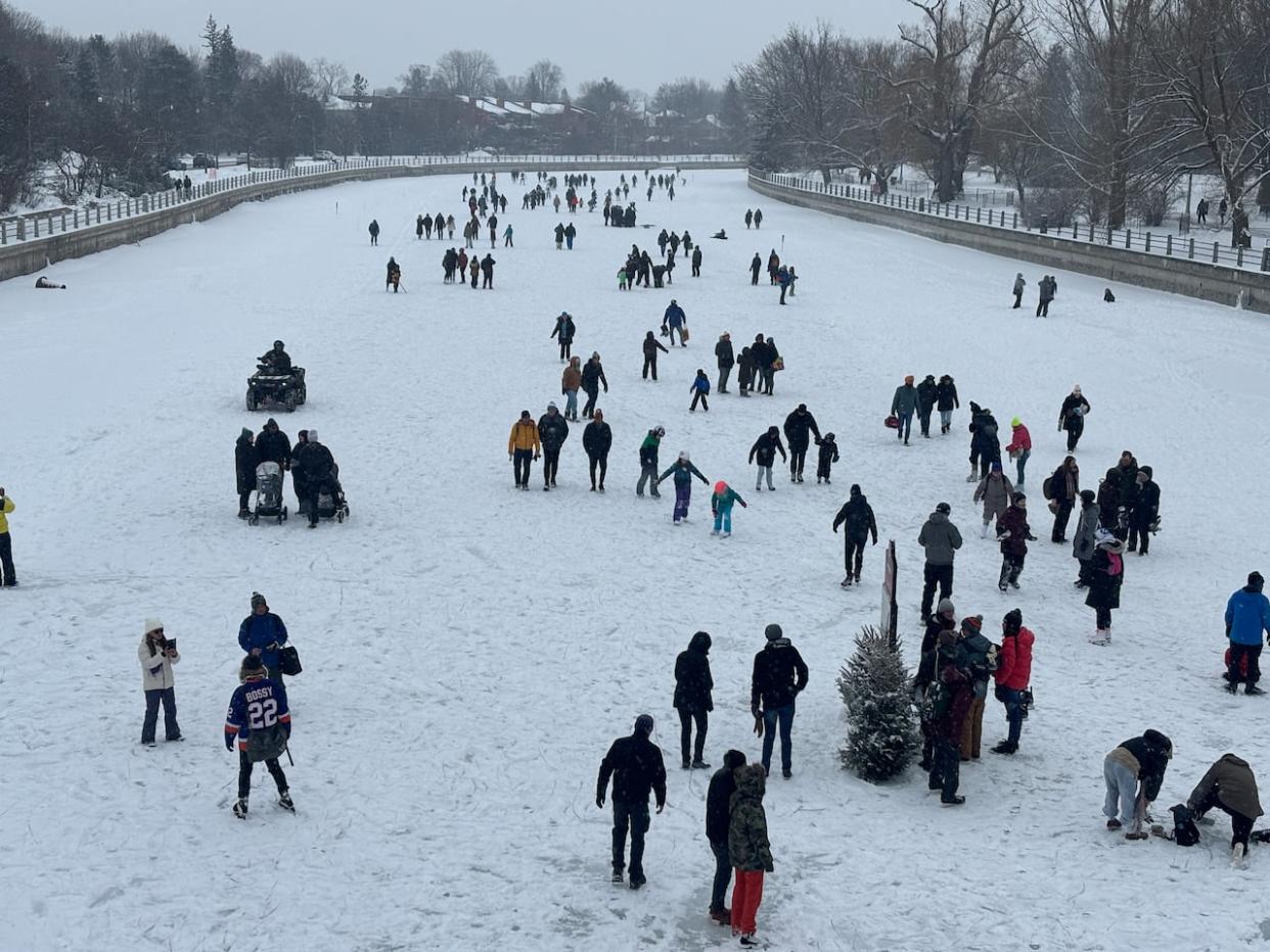 People skate and walk along the Rideau Canal Skateway on Feb. 18, 2024. The NCC recommends 'walking over skating' because the ice is in 'very poor condition.' (Félix Pilon/CBC - image credit)