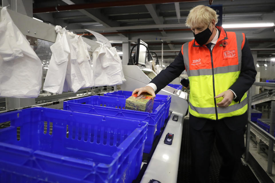 Britain's Prime Minister Boris Johnson loads produce into baskets during a visit to a tesco.com distribution centre in London, Wednesday, Nov. 11, 2020. (AP Photo/Kirsty Wigglesworth, pool)