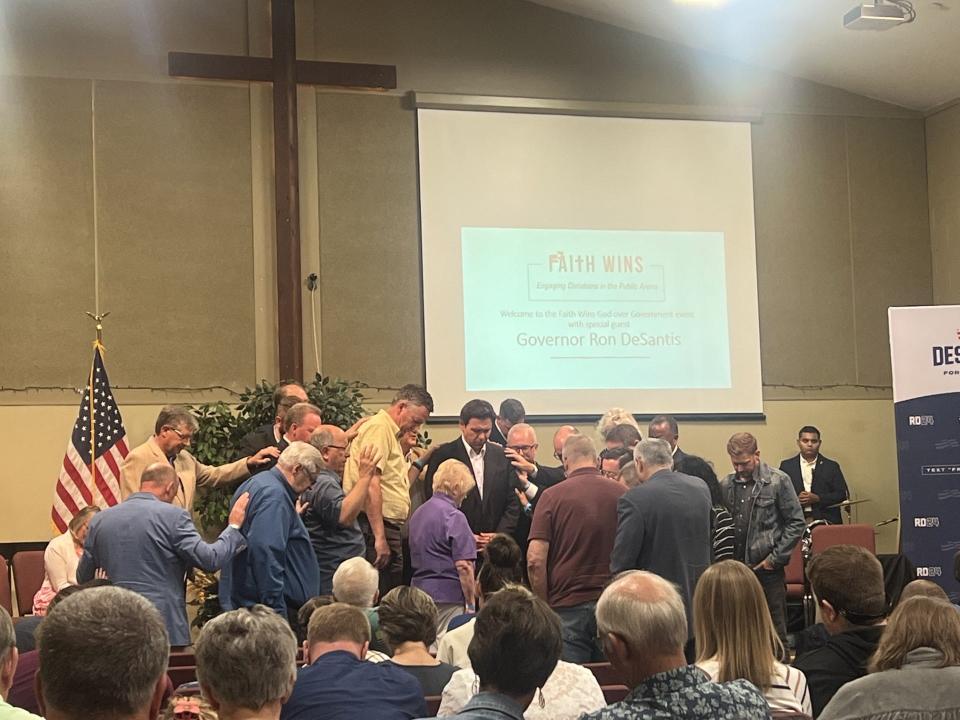 A crowd prays around Florida Gov. Ron DeSantis as he holds a campaign event at a church in Des Moines, Iowa on Sept. 16, 2023.