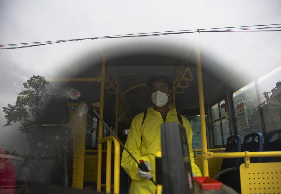 A Nepalese bus driver disinfects his vehicle before starting service in Kathmandu, Nepal, Tuesday, July 14, 2020. After restrictions on public transportation for almost four month to control the spread of the new coronavirus, Nepal's government has allowed public vehicles to operate within certain districts and inside Kathmandu valley, following safety norms. (AP Photo/Niranjan Shrestha)