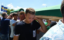 <p>Bosnian Muslims, survivors of Srebrenica 1995 massacre, as well as other visitors, carry one of many caskets containing the remains of their relatives, before final burial at memorial cemetery in village of Potocari, near the eastern Bosnian town of Srebrenica, on July 11, 2017. (Photo: Elvis Barukcic/AFP/Getty Images) </p>