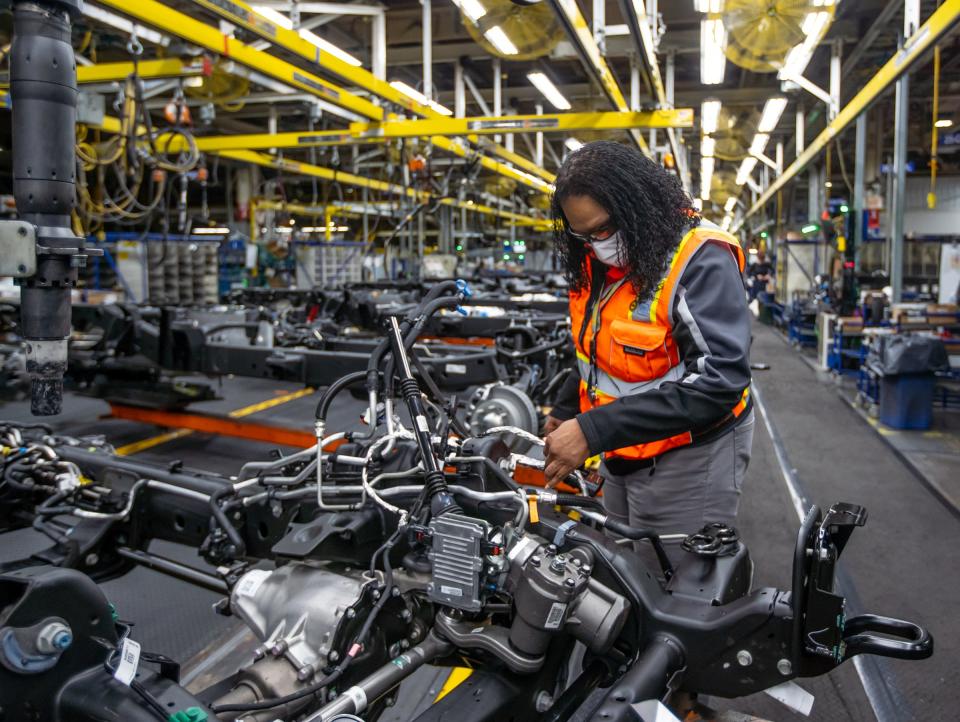 Launch Electrical Lead Process Coordinator LaTonya Jones checks parts of a harness and an actuator hose on a Chevy truck chassis sitting on an assembly line at General Motors Flint Assembly on April 16, 2021. GM started its own college last year to train workers to build EVs. GM will soon hire from the 30 graduates of the college at the plants that will launch the new EVs. The jobs will involve setting up the equipment for installation of parts on EVs, checking wire harnesses and other specialized jobs.