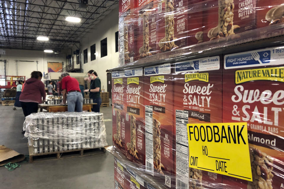 FILE - A pallet of food awaits processing as volunteers work in the background to label cans of beans for redistribution at Roadrunner Food Bank in Albuquerque, N.M., Thursday, May 7, 2020. Supporting nonprofits on GivingTuesday this year could have a bigger impact than usual as nonprofits and industry groups say donations so far are down compared with previous years. Many organizations will be looking to make up the difference on GivingTuesday, which is the Tuesday after Thanksgiving, Nov. 28, 2023. (AP Photo/Susan Montoya Bryan, File)