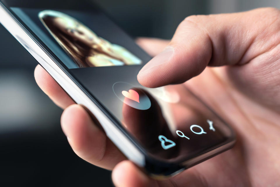 An up-close photo of a hand holding a smartphone on a dating app