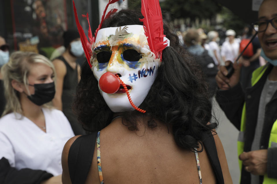 A protestor wears a mask on the back of her head which says "no" in French as she attends a demonstration in Paris, France, Saturday, July 31, 2021. Demonstrators gathered in several cities in France on Saturday to protest against the COVID-19 pass, which grants vaccinated individuals greater ease of access to venues. (AP Photo/Adrienne Surprenant)