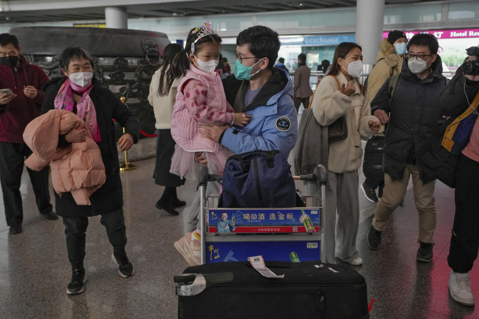 A man wearing a face mask meets with his child as he arrives from Hong Kong at Terminal 3 international arrival hall of the Beijing Capital International Airport in Beijing, Sunday, Jan. 8, 2023. Travelers crossing between Hong Kong and mainland China, however, are still required to show a negative COVID-19 test taken within the last 48 hours, a measure China has protested when imposed by other countries. (AP Photo/Andy Wong)