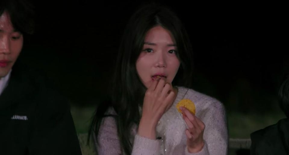Ji-yeon looks away while eating a piece of tortilla chip
