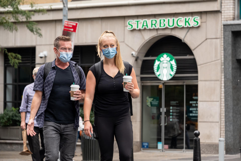 NEW YORK, NEW YORK - SEPTEMBER 29:  People wear protective face masks outside Starbucks in Union Square as the city continues Phase 4 of re-opening following restrictions imposed to slow the spread of coronavirus on September 29, 2020 in New York City. The fourth phase allows outdoor arts and entertainment, sporting events without fans and media production. (Photo by Noam Galai/Getty Images)