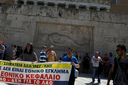 Workers of the Public Power Corporation (PPC) hold a banner as they protest over planned sale of coal-fired units on the Tomb of the Unknown Soldier in front of the parliament building in Athens, Greece, April 25, 2018. The banner reads "The sell-off of PPC is a national crime". REUTERS/Alkis Konstantinidis