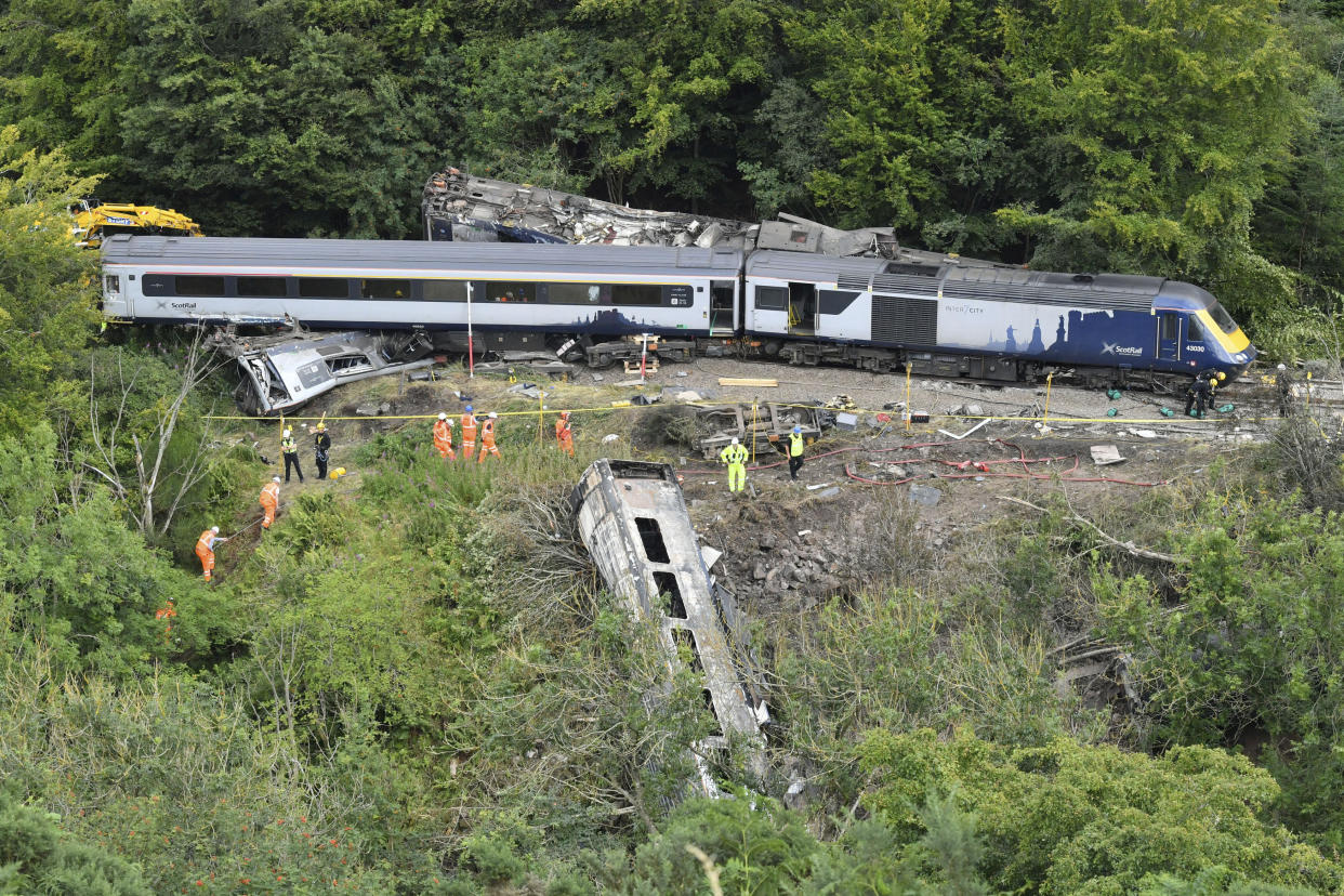 Emergency services inspect the scene following a train derailment near Stonehaven, Scotland, Thursday, Aug. 13, 2020. British Transport Police say three people died and six were taken to the hospital with injuries after a passenger train derailed in northeast Scotland after heavy rain and flooding. The train driver and conductor are believed to be among the dead, but formal identification is pending. (Ben Birchall/PA via AP)