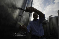 In this image taken on Monday, Oct. 15, 2018, wine grower Adelino Pizzobon spills Prosecco from a silos, at the Case Paolin farm, in Volpago del Montello, Italy. Prosecco has become the best-selling sparkling wine in the world, and experts say it is eroding the more casual corner of champagne's market while aiming higher. Its production eclipsed champagne's five years ago and is now 75 percent higher at 544,000 bottles three-quarters of which for export. (AP Photo/Luca Bruno)