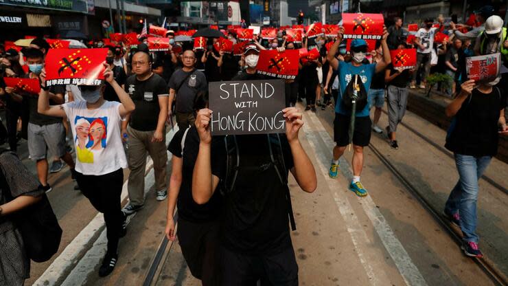 Demonstranten mit Protestplakaten, die sich gegen die chinesische Regierung wenden. Foto: dpa