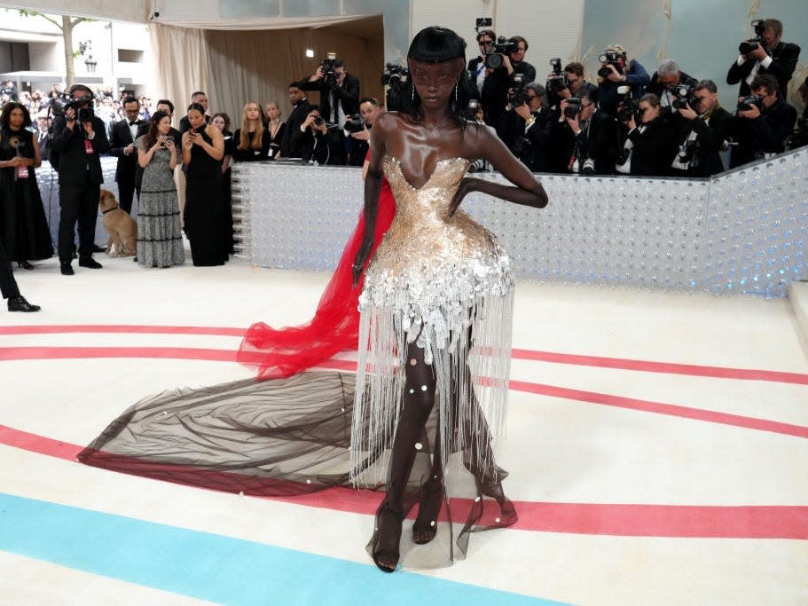 Anok Yai attends the 2023 Met Gala weawring a voluminous metallic gown with a train.