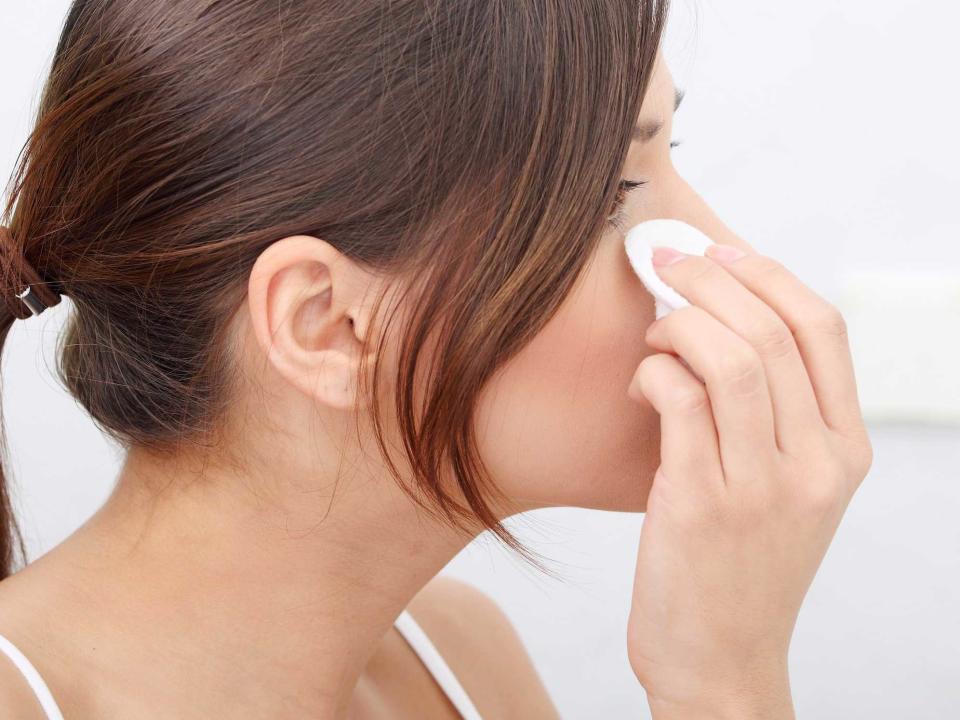 woman cleaning face cotton swab ball bathroom