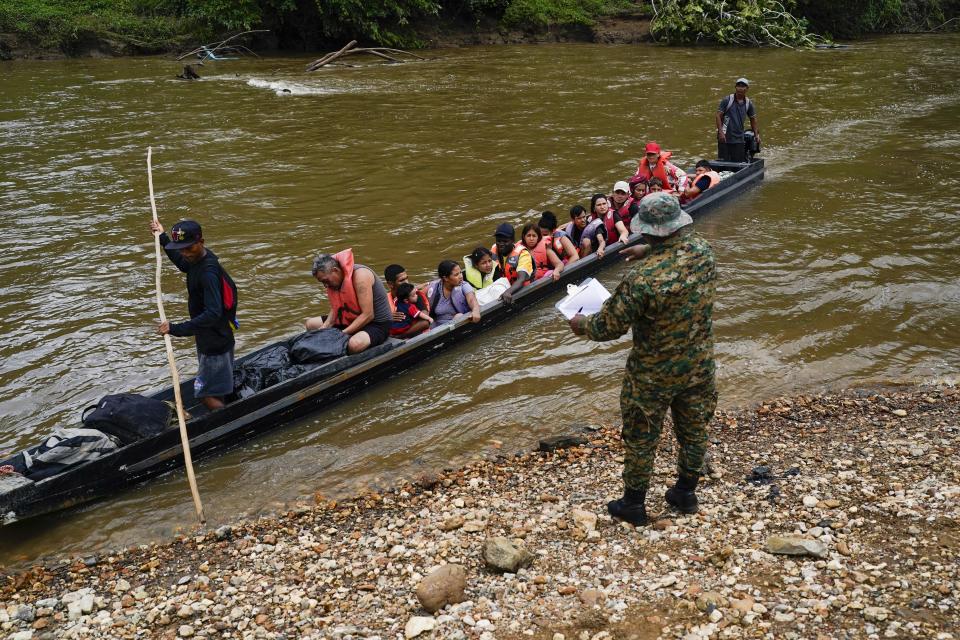 Migrants heading north arrive to Lajas Blancas where a Panamanian border police officer stands on the bank of the Chucunaque River in the Darien province, Panama, Friday, Oct. 6, 2023, after walking across the Darien Gap from Colombia. (AP Photo/Arnulfo Franco)