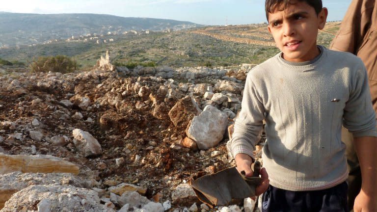 A Syrian boy carries a piece of metal next to a crater where a Scud missile hit in the town of Nasiriyeh on December 13, 2012. Moscow has acknowledged that the Syrian regime, its longtime ally, might lose its battle with Arab- and Western-backed rebels, 21 months into a conflict that has cost tens of thousands of lives