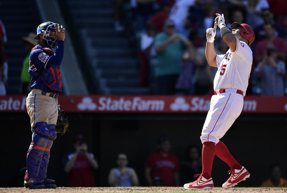 Los Angeles Angels' Albert Pujols, right, gestures after hitting a solo home run as Texas Rangers catcher Isiah Kiner-Falefa stands at the plate during the seventh inning of a baseball game Saturday, April 6, 2019, in Anaheim, Calif. (AP Photo/Mark J. Terrill)