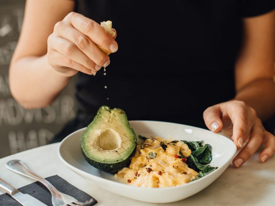 A woman eating eggs and avocado.