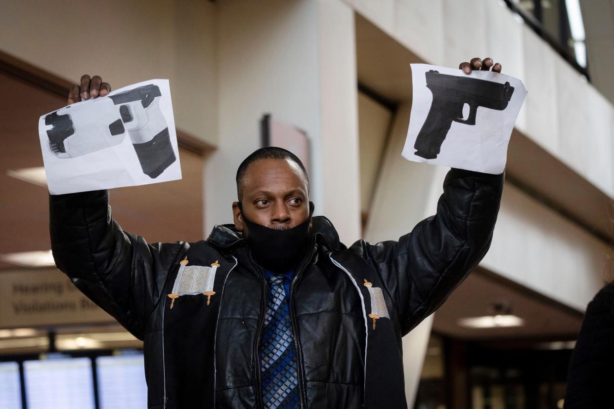 Rabbi Michael Ben Yosef holds up photos of a gun and a taser at a press conference in the lobby of the Hennepin County Government Center on Friday, Dec. 17, 2021, in Minneapolis. 