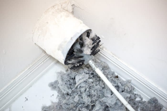 Lint being removed with a brush from a dryer vent