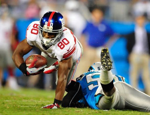 Victor Cruz of the New York Giants dives over James Anderson of the Carolina Panthers for extra yardage during play on September 20, 2012 in Charlotte, North Carolina. The Giants won 36-7