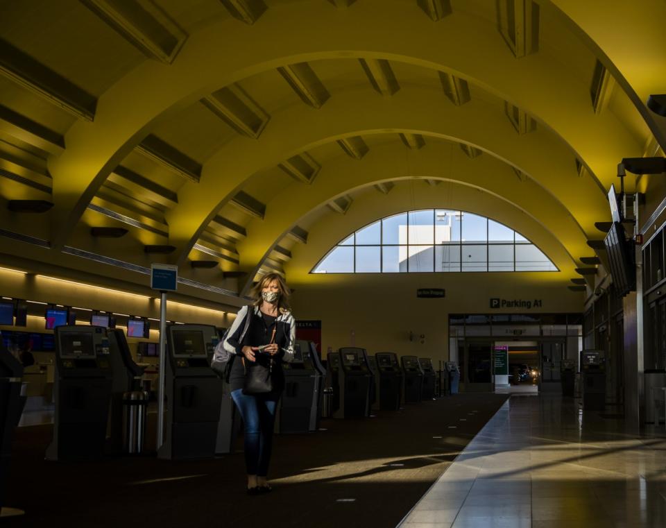 A traveler wearing a mask makes her way through John Wayne Airport in Orange County.