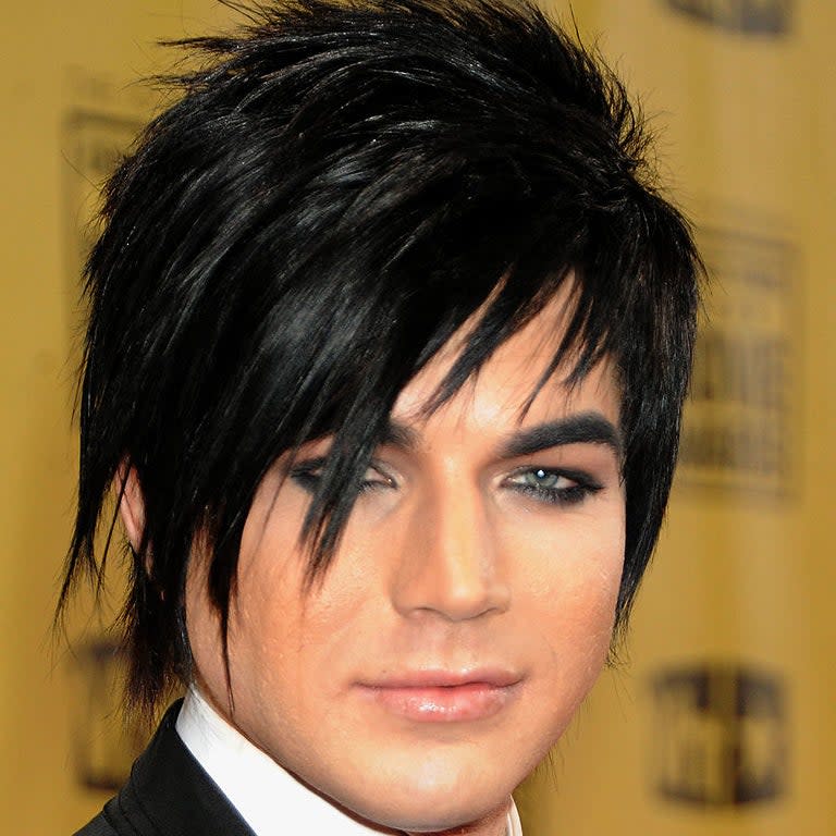 Adam with spiked black hair and eye makeup, wearing a suit and tie