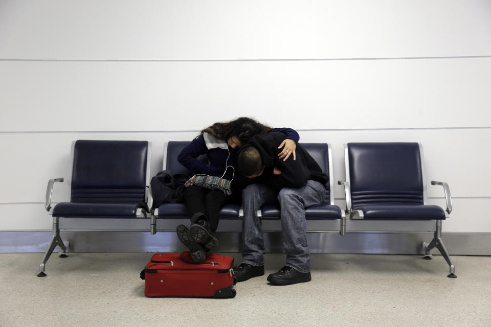 In this Sunday, Jan. 5, 2014, file photo, Michelle Rivas, left, and Danny Ruiz do their best to get comfortable after being stranded at Lambert-St. Louis International Airport because a snow storm canceled their flight home to Miami, in St. Louis. A series of winter storms have led airlines to cancel more than 33,000 flights during the first three weeks of this year. That's more cancellations than in January 2013 and January 2012 combined, according to masFlight, a data and software company specializing in airline operations. (AP Photo/Jeff Roberson, File)