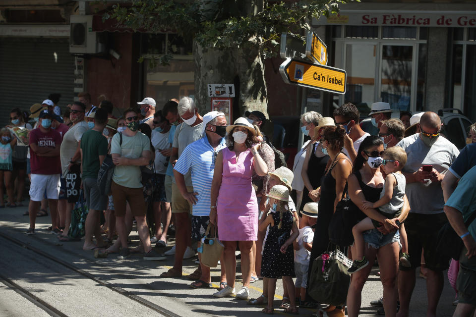 Tourists wait to board a tram in town of Sóller in the Balearic Island of Mallorca, Spain, Monday, July 27, 2020. Britain has put Spain back on its unsafe list and announced Saturday that travelers arriving in the U.K. from Spain must now quarantine for 14 days. (AP Photo/Joan Mateu)