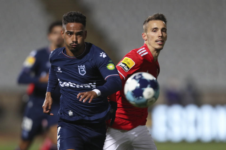 Belenenses' Diogo Calila vies for the ball with Benfica's Alejandro Grimaldo, right, during the Portuguese Primeira Liga soccer match between Belenenses SAD and SL Benfica, Saturday, Nov. 27, 2021. Belenenses SAD started the match with only nine players due to a coronavirus outbreak. Portuguese health authorities on Monday, Nov. 29, 2021, identified 13 cases of omicron, the new coronavirus variant spreading fast globally, among members of Belenenses SAD. (AP Photo/Pedro Rocha)