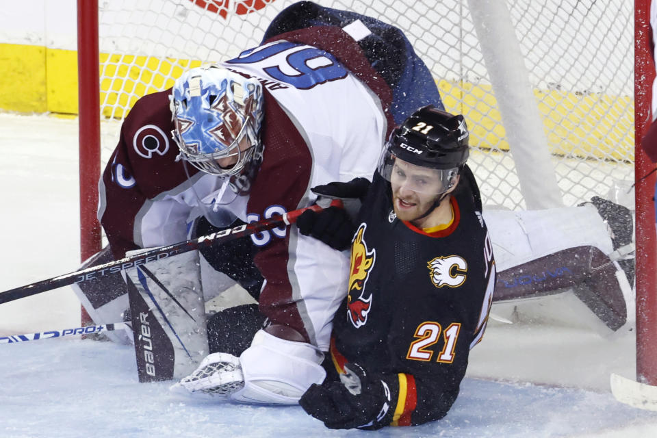 Calgary Flames' Kevin Rooney, right, slides into Colorado Avalanche goalie Justus Annunen dduring the second period of an NHL hockey game Tuesday, March 12, 2024, in Calgary, Alberta. (Larry MacDougal/The Canadian Press via AP)