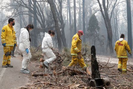 Firefighters and members of a volunteer search and rescue crew approach a house destroyed by the Camp Fire in Paradise, California, U.S., November 13, 2018. REUTERS/Terray Sylvester