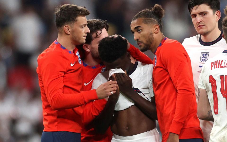 England's Bukayo Saka looks dejected after losing the penalty shootout as teammates console him - REUTERS