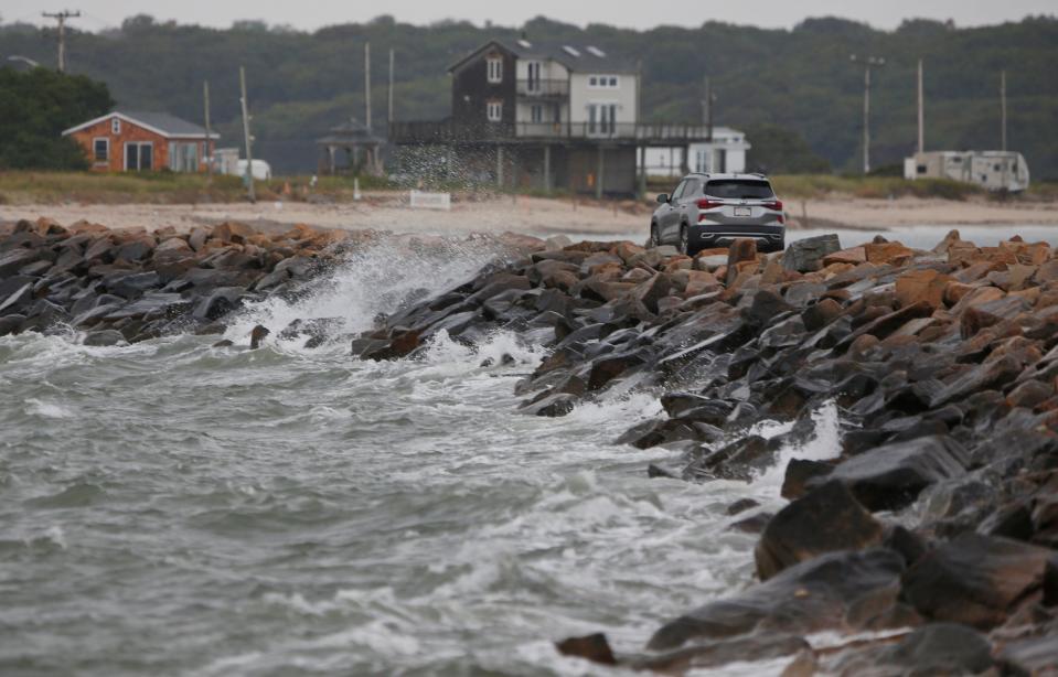 Waves caused by Hurricane Lee crash onto the rocks as a vehicle crosses the Gooseberry Island causeway in Westport.