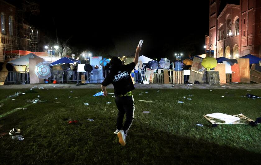 LOS ANGELES, CALIFORNIA - May 1: A pro-Israeli supporter throws a bottle of water at the Pro-Palestinian encampment at UCLA early Wednesday morning. (Wally Skalij/Los Angeles Times)