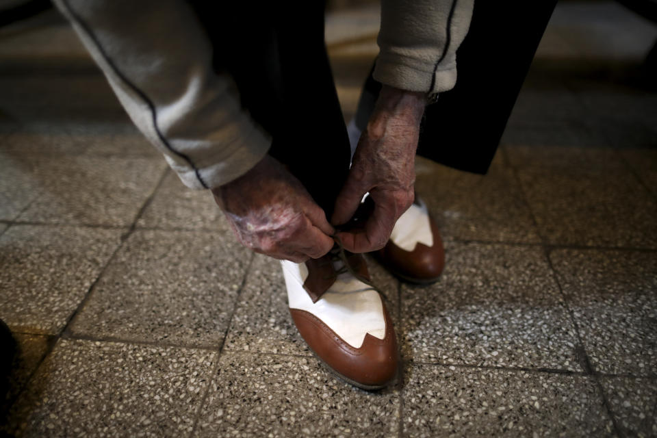 In this Aug. 15, 2019 photo, 99-year-old James McManus laces up in preparation for dancing tango, in Buenos Aires, Argentina. McManus says he discovered the dance rather recently for his long life. It was in 2002 when he saw a couple dancing in Ireland where he lives. Since then, he couldn’t stop. (AP Photo/Natacha Pisarenko)